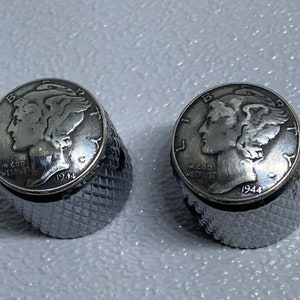 May include: Two silver-toned guitar tuning knobs with a 1944 Walking Liberty Half Dollar coin design. The knobs have a knurled, textured surface.