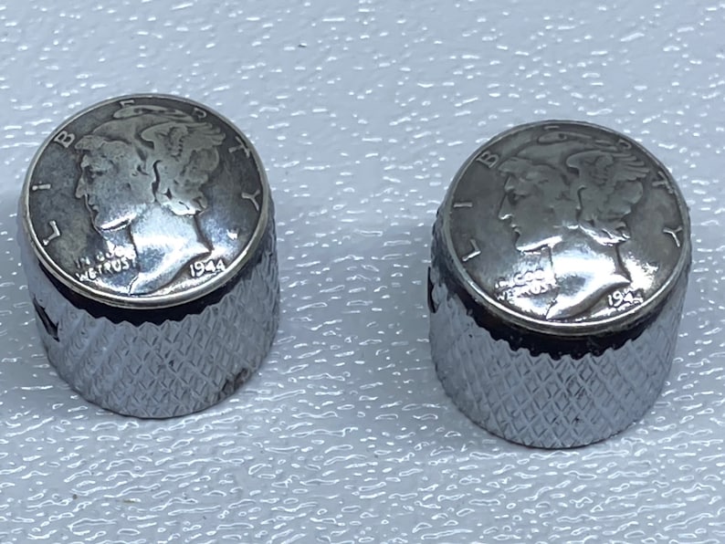 May include: Two silver-colored guitar knobs with a 1944 Mercury dime embedded in the top of each knob.