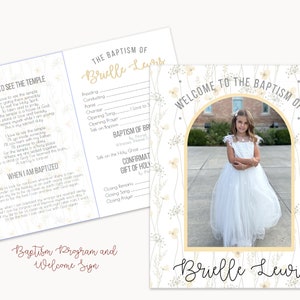 Op de afbeelding: Een wit welkomsbord met een bloemige rand en een foto van een jong meisje in een witte jurk. Het bord staat "Welkom op de doop van Brielle Lewis".