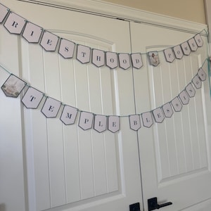 May include: Two banners with white pennants strung across a white door. The top banner reads "PRIESTHOOD POWER" and the bottom banner reads "TEMPLE BLESSINGS" in black letters. The banners are strung with a teal string.