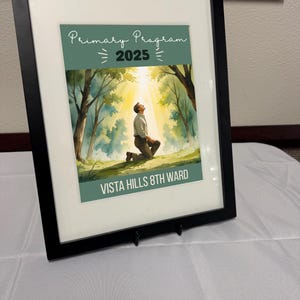 Può includere: Stampa incorniciata in nero con un'illustrazione ad acquerello di una persona inginocchiata in una foresta, illuminata dalla luce del sole. Il testo "Primary Program 2025" e "Vista Hills 8th Ward" è presente.
