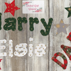 May include: A set of fabric letters spelling "Harry Elsie Dad" with a star pattern. The letters are green, white, and red with gold stars. There is a small business card with the text "Orchard Craft Company" in the top right corner.