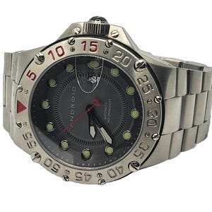 May include: A silver and black Android automatic wristwatch with a black face and red accents. The watch has a rotating bezel with numbers from 5 to 60. The watch face has a date window and the words "Android", "Automatic", and "WR 200M/640FT".