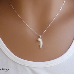 The model shows a minimal silver necklace 16.5" made with Sterling silver feather and tiny ivory pearl on a Sterling silver Rolo chain