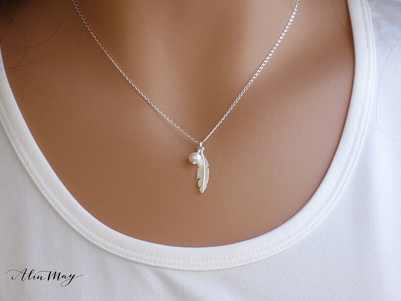 The model shows a minimal silver necklace 16.5" made with Sterling silver feather and tiny ivory pearl on a Sterling silver Rolo chain