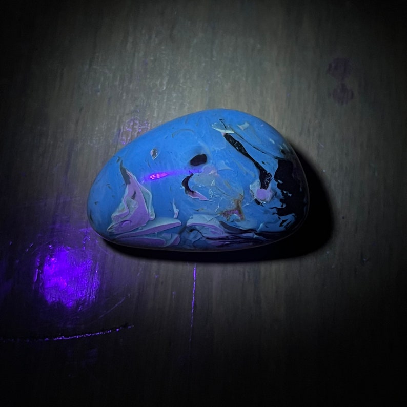 May include: A blue, white, and black marbled stone with a smooth, rounded surface.