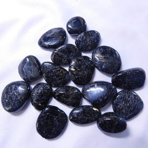 May include: A collection of smooth, dark blue and black tumbled stones with a shimmery, iridescent finish. The stones are oval-shaped and have a natural, polished look.