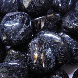 May include: A collection of black obsidian tumbled stones with a shimmering, iridescent effect. The stones are smooth and polished, with a variety of shapes and sizes.