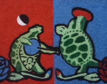 May include: Two green turtles with brown outlines, one on a red background and one on a blue background. The turtle on the red background is holding a blue circle. The turtle on the blue background is holding a red circle. Both turtles have a flower behind them.