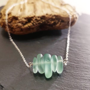 May include: A silver chain necklace with a cluster of light green sea glass beads.