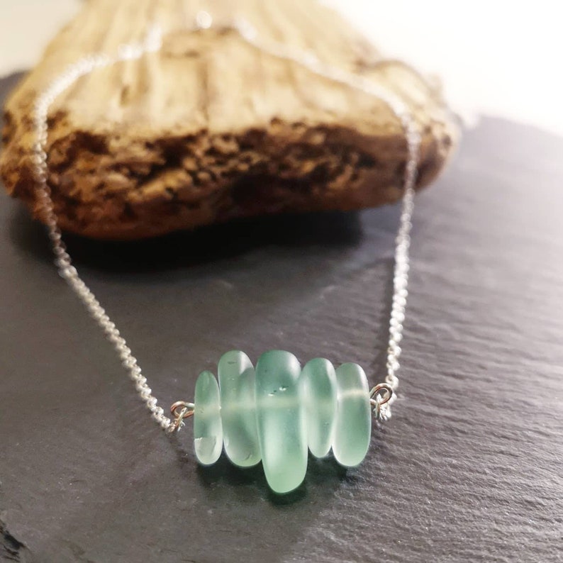 May include: A silver chain necklace with a cluster of light green sea glass beads.