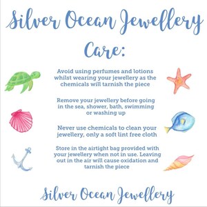 May include: A white card with blue text that reads "Silver Ocean Jewellery Care:" and provides instructions for caring for jewelry. The card is decorated with illustrations of a turtle, a starfish, a seashell, a fish, an anchor, and a seashell.
