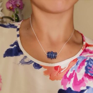May include: A silver chain necklace with a pendant made of five blue glass beads. The beads are arranged in a staggered pattern.
