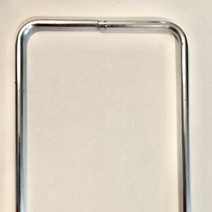 May include: A silver metal frame with rounded corners. The frame is made of a single piece of metal that is bent into a rectangle shape.