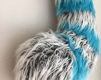May include: A fluffy blue and white striped tail with a gray and white paw at the end.