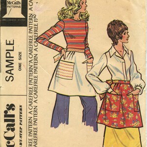 May include: A vintage sewing pattern for a short apron. The pattern features two women wearing the apron, one with a striped shirt and the other with a white shirt. The pattern is labeled "Misses' and Junior Short Apron".