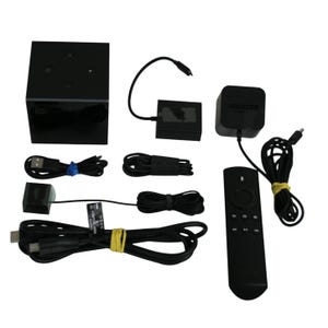 Può includere: Un set di accessori Amazon Fire TV Cube neri, tra cui un cubo, un telecomando, adattatori di alimentazione e cavi. Il telecomando ha diversi pulsanti e un'icona del microfono.