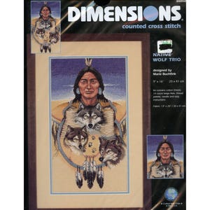 May include: A Dimensions counted cross stitch kit titled "Native Wolf Trio." The design features a Native American person with three wolves. The kit includes cotton thread, a 14-count beige Aida, a thread palette, a needle, and instructions. The fabric size is 13 x 20 inches.