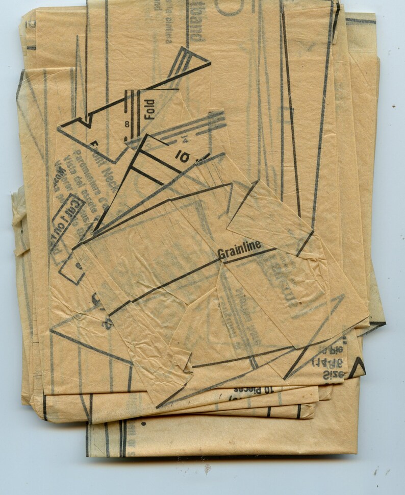 May include: A stack of vintage sewing pattern pieces in beige paper with black printed lines and text. The text includes "Fold", "Front Neck", "Grainline", and "10 Pieces".