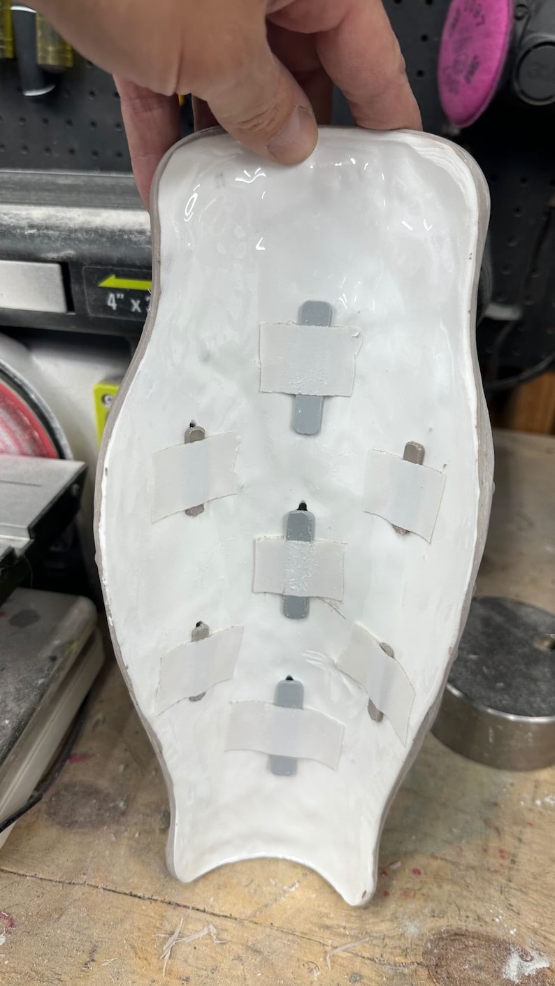 May include: White ceramic mold with six gray adhesive strips attached to the inside. The mold is shaped like a human leg.