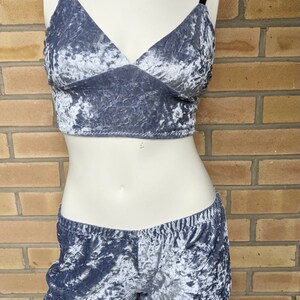 May include: A two-piece set of gray crushed velvet lingerie. The top is a cropped bra with thin straps and a V-neckline. The shorts are high-waisted and have a wide waistband.
