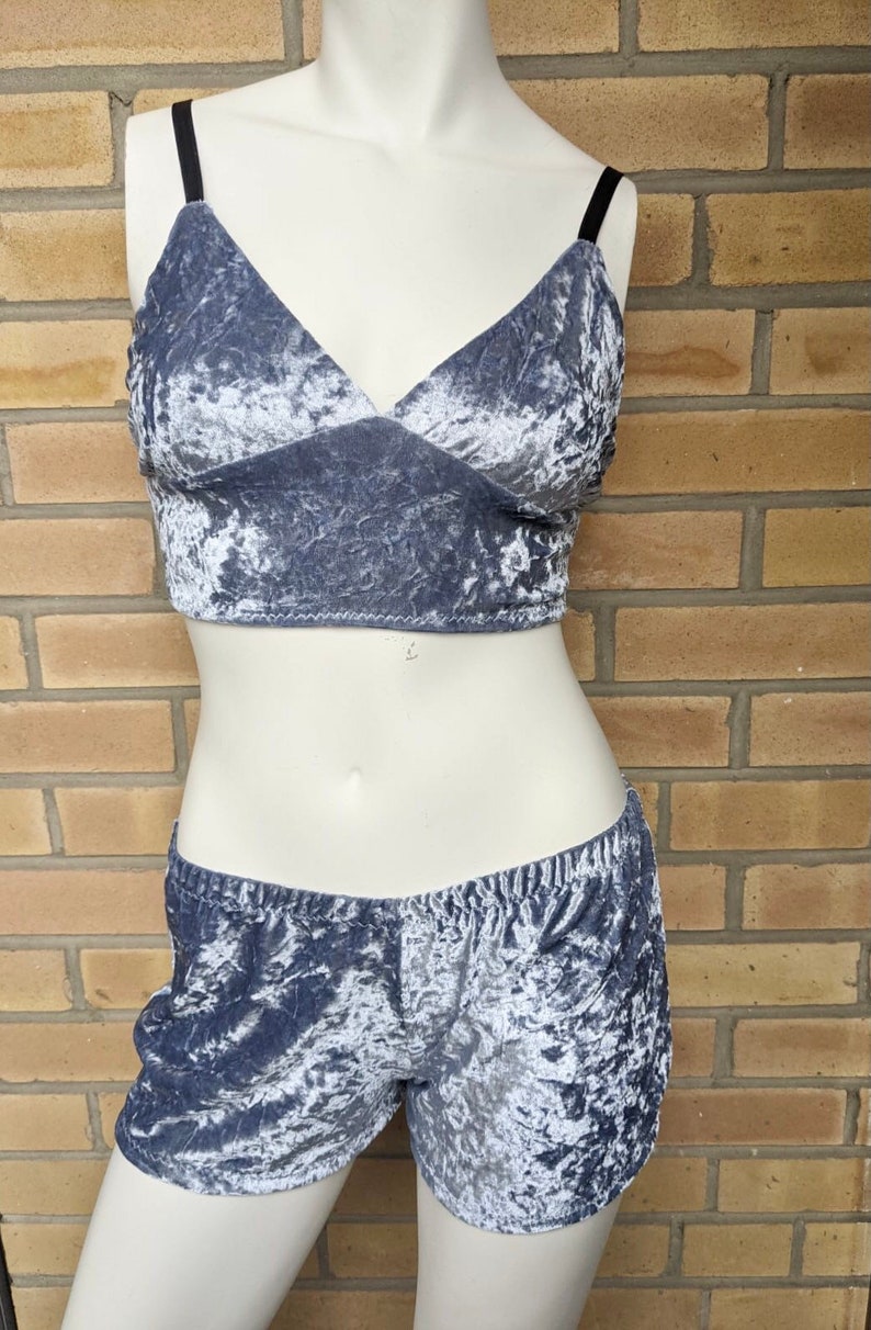 May include: A two-piece set of gray crushed velvet lingerie. The top is a cropped bra with thin straps and a V-neckline. The shorts are high-waisted and have a wide waistband.
