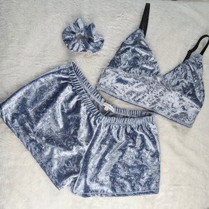 May include: A gray crushed velvet pajama set with a matching scrunchie. The set includes a cropped top with a V-neck and shorts.