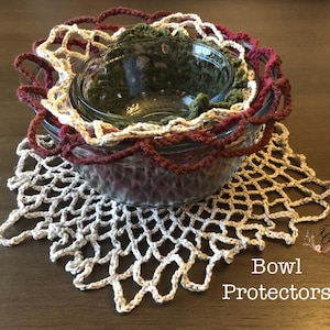 May include: A set of crochet bowl protectors in a variety of colors. The protectors are in shades of cream, burgundy, and green. The text "Bowl Protectors" is visible in the lower right corner.