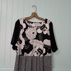 May include: A black and white floral print dress with a black and white gingham skirt. The dress has short sleeves and a scoop neck.