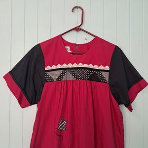 May include: A red, black, and white patchwork dress with short sleeves and a lace trim. The dress has a gathered skirt and a loose fit.