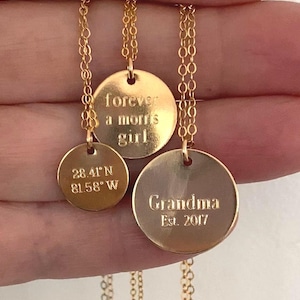 May include: Three gold-colored disc necklaces. One pendant reads "forever a morris girl", another displays coordinates, and the third says "Grandma Est. 2017". Each disc hangs from a delicate chain.