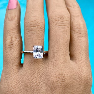May include: A gold ring with a large, clear, rectangular-shaped gemstone.