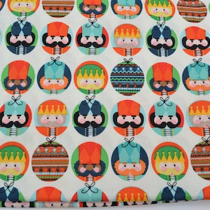 Puede incluir: Tela blanca con un patrón repetido de adornos de cascanueces coloridos. Cada adorno presenta un diseño diferente, que incluye un sombrero rojo, un sombrero azul, un sombrero verde y una corona dorada. La tela es perfecta para proyectos de manualidades, como acolchar, coser y scrapbooking.