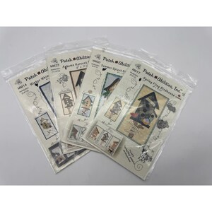 Op de afbeelding: Een verzameling Patch Abilities knutselpakketten in transparante plastic verpakkingen. Elke set bevat een vogelhuisontwerp met seizoensgebonden thema's zoals Winter Whim, Autumn Harvest en Summer Splash. De sets zijn voorzien van het Patch Abilities logo en productcodes.