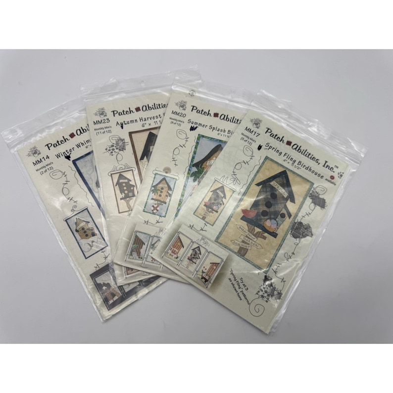 Op de afbeelding: Een verzameling Patch Abilities knutselpakketten in transparante plastic verpakkingen. Elke set bevat een vogelhuisontwerp met seizoensgebonden thema's zoals Winter Whim, Autumn Harvest en Summer Splash. De sets zijn voorzien van het Patch Abilities logo en productcodes.