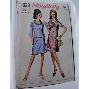 Può includere: Modello di cucito vintage Simplicity numero 7029 per abiti da donna. Il modello include due stili: un abito blu con scollo rotondo e un abito rosa floreale con un fiocco.
