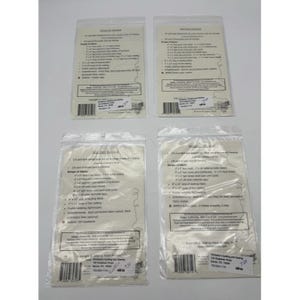 Op de afbeelding: Vier doorzichtige plastic zakken met quiltmaterialen en instructies. Elke zak heeft een witte papieren inlegger met een lijst van benodigde materialen voor een quiltproject. De zakken zijn gerangschikt op een wit oppervlak.