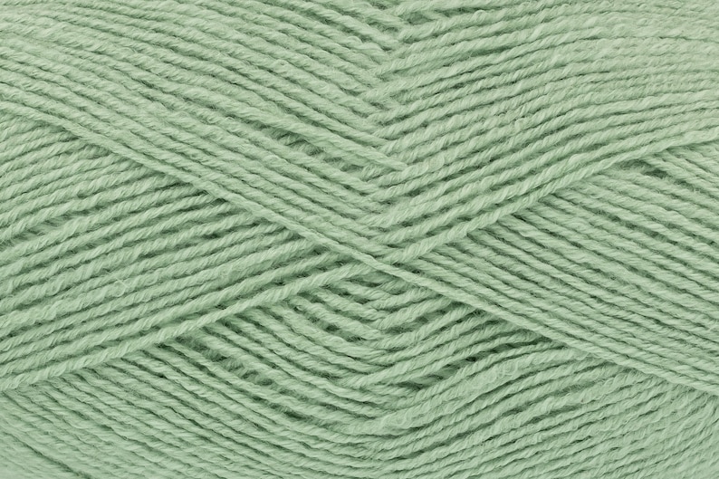 May include: A skein of soft, light green yarn. The yarn is made of natural fibers and has a smooth texture.