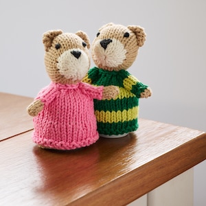 May include: Two knitted teddy bears wearing colorful striped sweaters. The bear on the left is wearing a pink sweater and the bear on the right is wearing a green and yellow striped sweater.