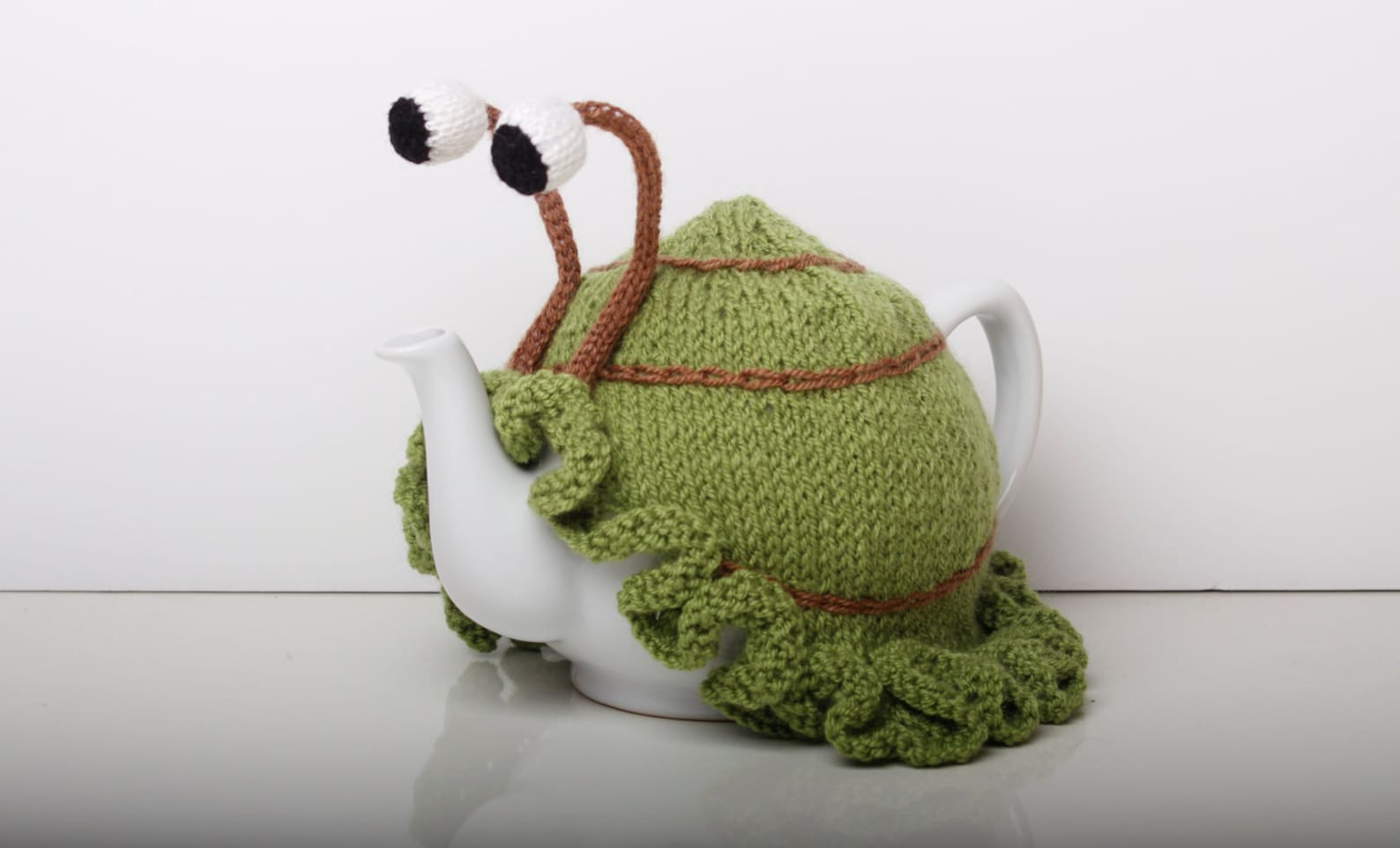 Knitted green snail tea cosy with frilly bottom. Washable fits Etsy