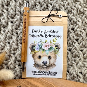 Könnte beinhalten: Eine Dankeskarte mit einem niedlichen Comic-Bären, der eine Blumenkrone trägt. Die Karte lautet "Danke für deine liebevolle Betreuung" und "Wildblumenmischung für Schmetterlinge und Bienen".