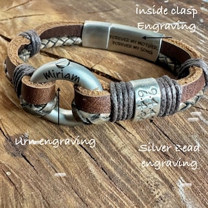 A personalized bracelet with engraved text and metal components, resting on a wooden surface.