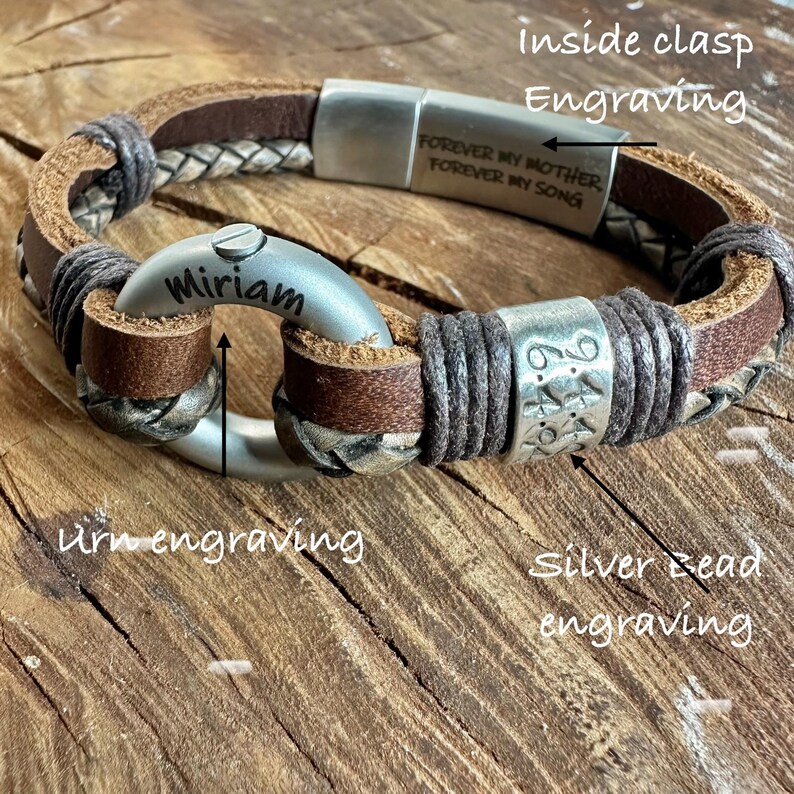 A personalized bracelet with engraved text and metal components, resting on a wooden surface.