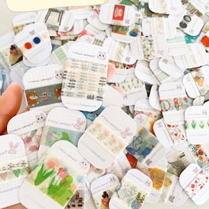 May include: A selection of washi tape samples featuring diverse designs, such as floral, geometric, and illustrated patterns. The samples are presented on small, white cards with the text "Mini sample" and "Washi Tape Samples".