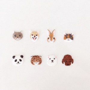 May include: Eight embroidered animal face patches, including a cat, dog, rabbit, panda, and polar bear. The patches feature detailed stitching and various colours, set against a white background.