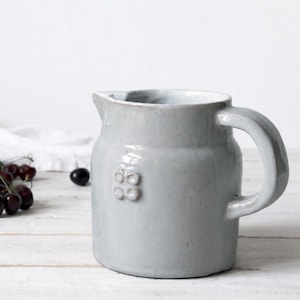 Vintage farmhouse stoneware jug with pale ceramic glaze and rustic handmade pottery character