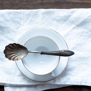 Puede incluir: Un juego de tres tazas de cerámica con un acabado moteado y mate. Las tazas son de color crema, gris claro y gris oscuro. Cada taza tiene un diseño simple y minimalista, ideal para café o té.