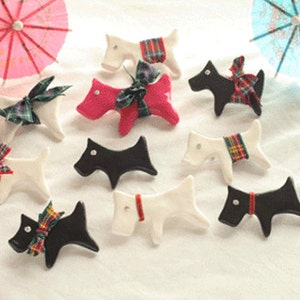 May include: A collection of nine ceramic dog figurines, each with a different color and pattern. The dogs are all in a sitting position with their tails curled up. Some of the dogs have plaid bows, while others have solid color bows.
