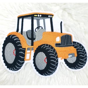 Könnte beinhalten: Gestickter Aufnäher eines orangefarbenen Traktors mit schwarzen Reifen und weißer Umrandung. Der Traktor hat einen grauen Innenraum und ein schwarzes Dach. Der Aufnäher ist zum Aufbügeln oder Aufnähen auf Stoff vorgesehen. Geeignet für Kinderkleidung oder Accessoires.