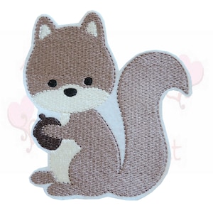 Könnte beinhalten: Gestickter Aufnäher mit einem Cartoon-Eichhörnchen in Braun-, Beige- und Weißtönen. Das Eichhörnchen hält eine braune Eichel. Der Aufnäher hat ein detailliertes, strukturiertes Aussehen mit einem weißen Rand.
